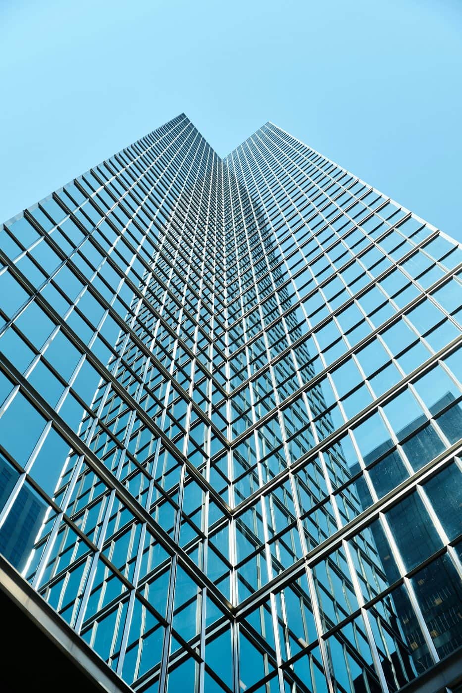 Glass office tower viewed from below against a clear sky